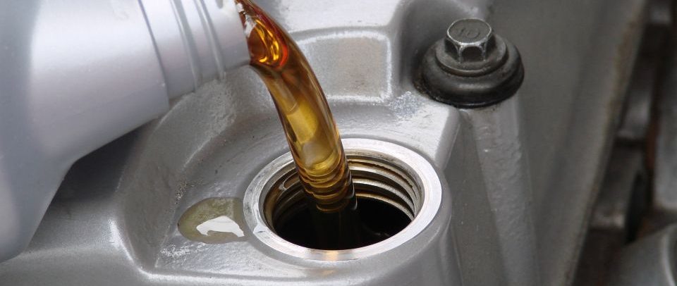 Fresh engine oil being poured into an engine filler port